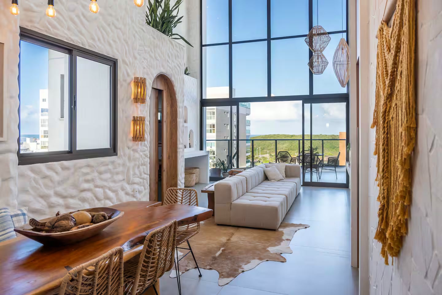 Sala de estar com pé-direito alto, janelas amplas e vista